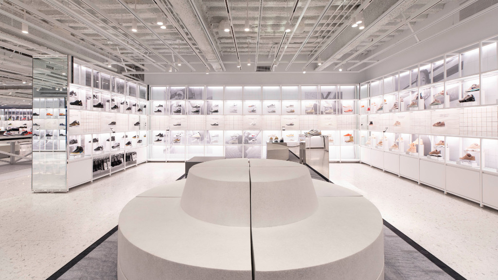 Circular white couch in front of a wall of sneakers in New Nike Flagship in NYC creating organic retail experiences