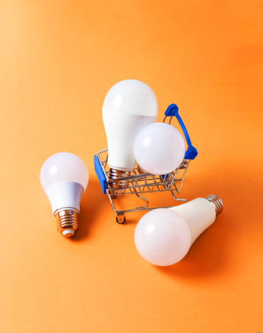 Two lightbulbs in a small cart with two lightbulbs on the ground over an orange background, holistic brand experiences